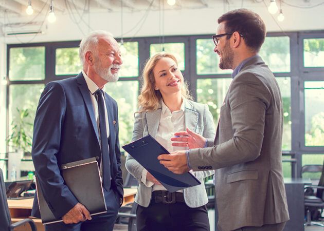 Mature-aged businessman talking with younger colleagues in office