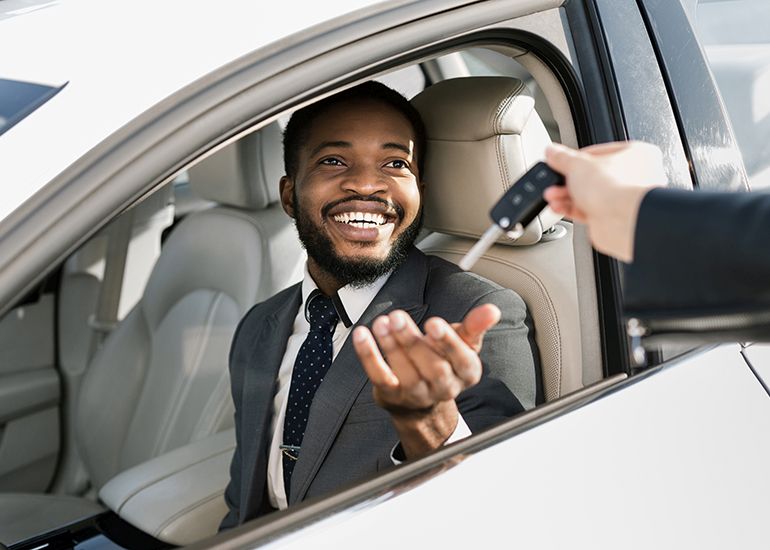 Happy young business man taking key to company car