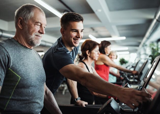 A group of seniors in gym with a young trainer doing cardio work out
