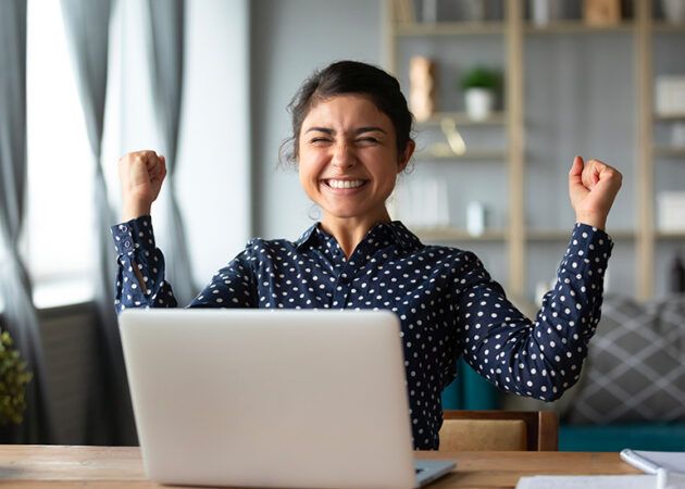 Excited woman fist-pumping with joy at laptop