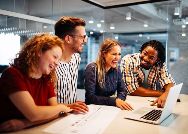Four young designers laughing and working together
