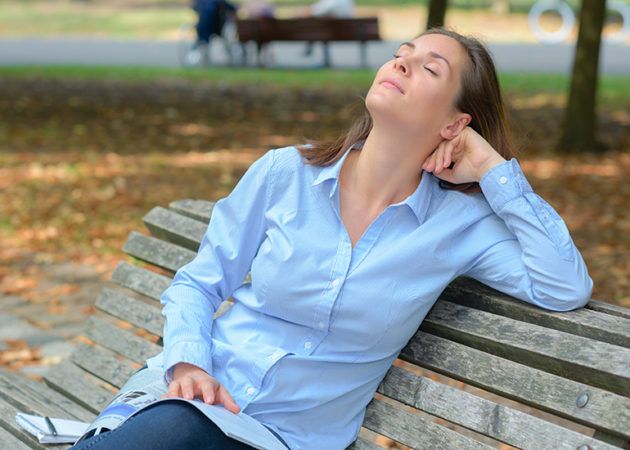 Woman relaxing with eyes closed on park bench