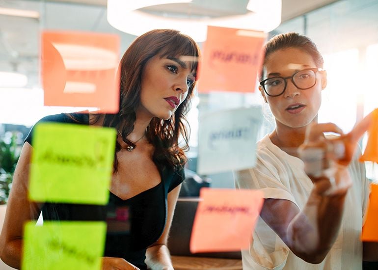 Two women discussing ideas on post-it notes