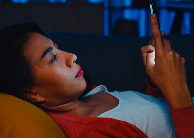 woman scrolling phone in bed at night