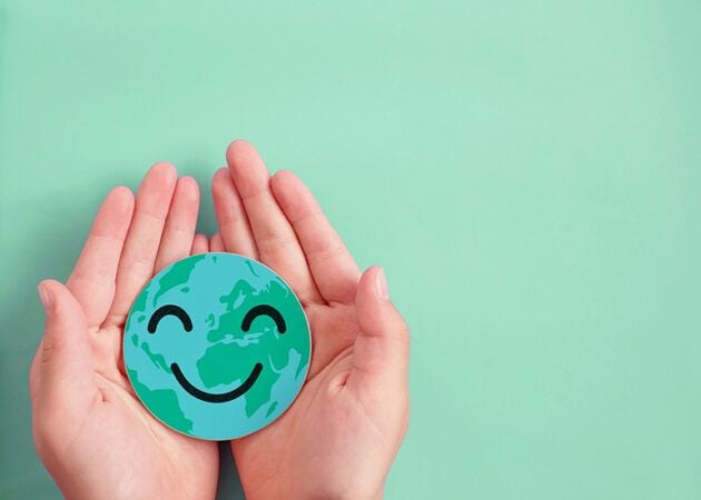 hands holding a paper earth globe with smiling face