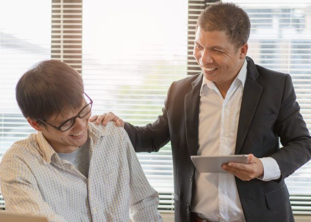 Supportive boss with hand on employee's shoulder
