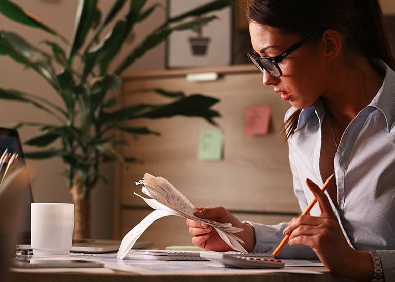 woman at desk calculating receipts and invoices