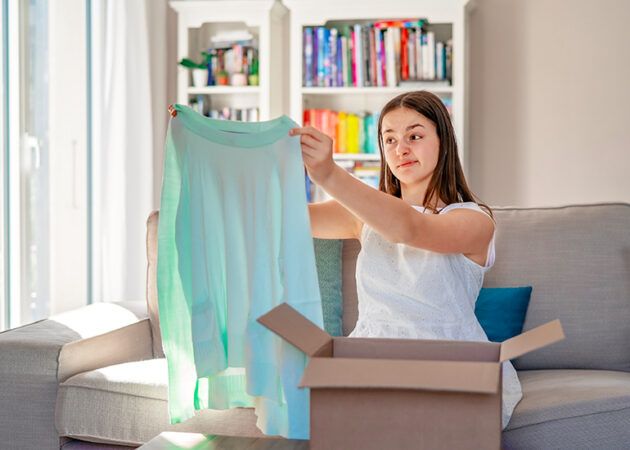 Unhappy young woman holding dress looking disappointed