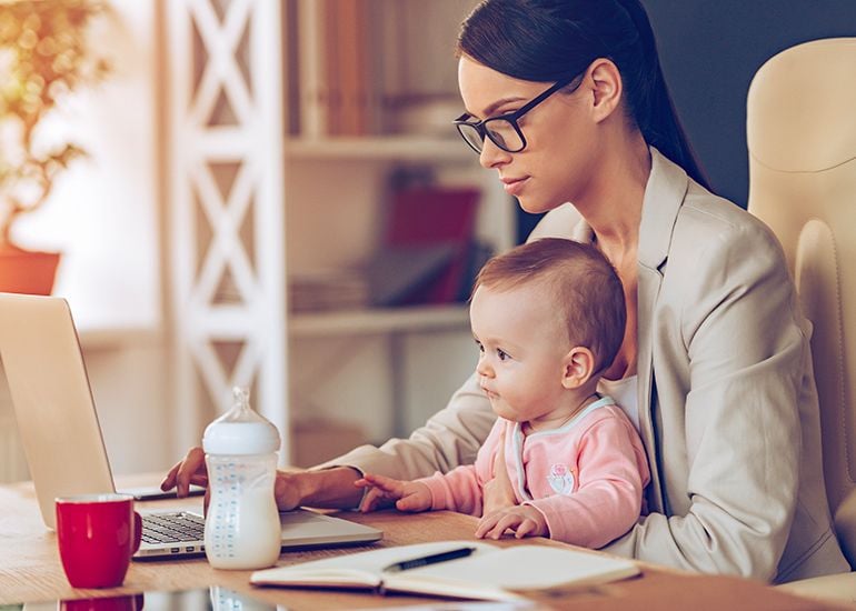 Working mother at desk with baby in her lap