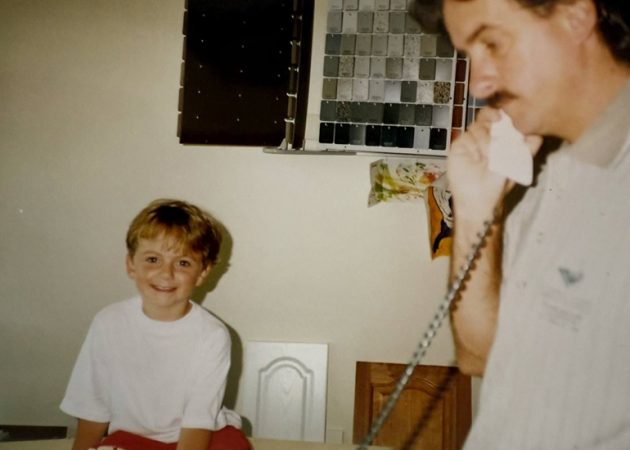 Mark Clarke working from his home office as son Jason watches on