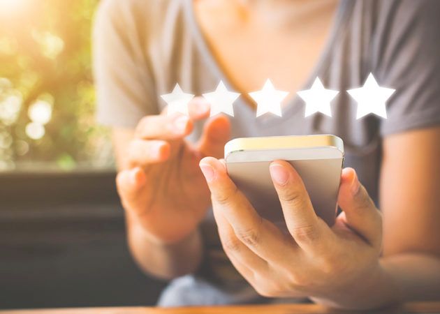 Woman posting 5 star review on phone