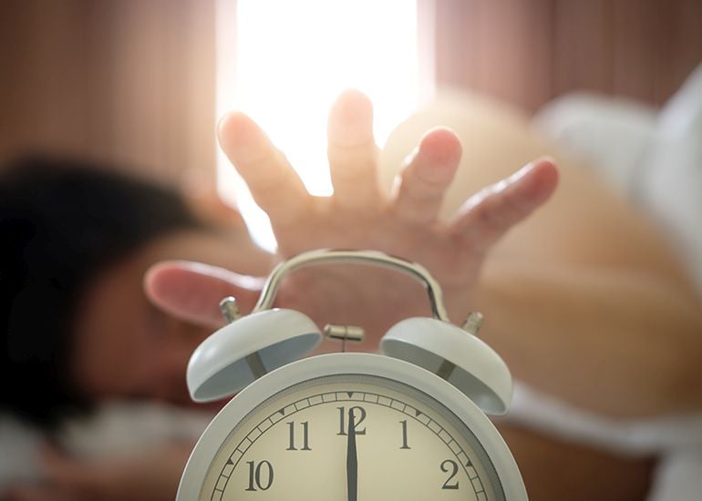 Reaching out hand to stop alarm clock