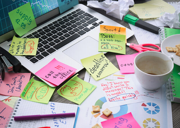 Messy desk with laptop and lots of notes