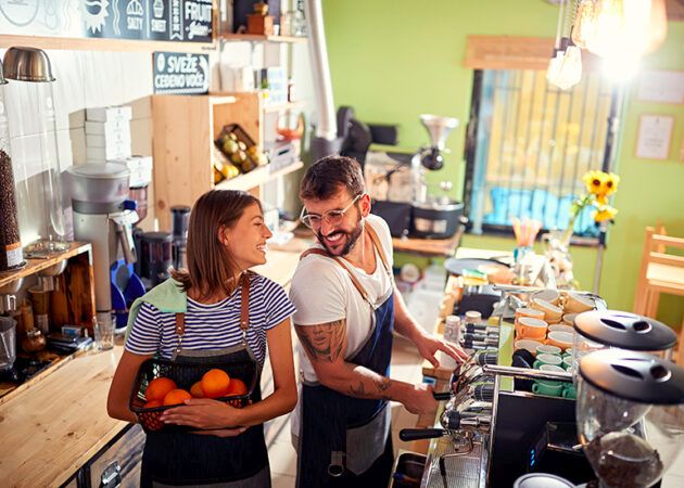 Happy young cafe owners working behind counter