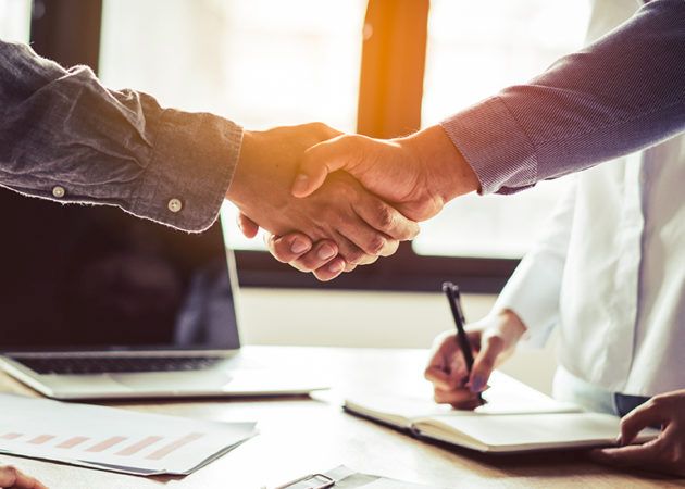 two men shaking hands as a lawyer signs contract