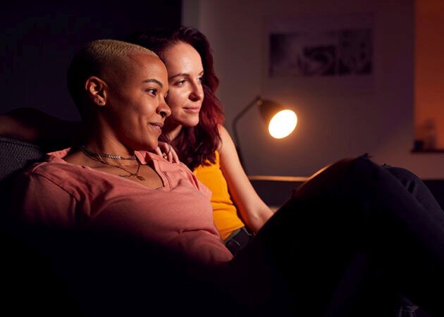 happy same sex couple watching tv in the evening