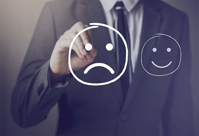 man drawing sad face on transparent whiteboard