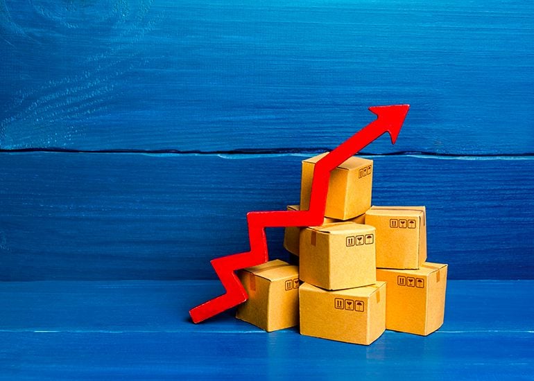 Stack of cardboard packing boxes with red arrow trending upwards