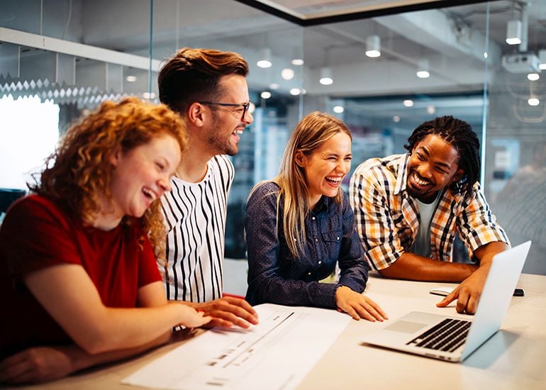 Four young designers laughing and working together