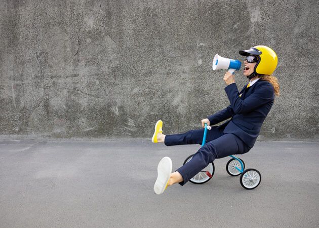 Woman riding child's tricycle while shouting into a megaphone