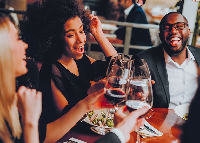 Group of friends clinking wine glasses at restaurant