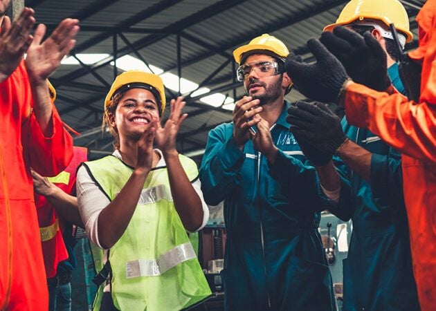 Work team in hard hats and hi-vis clapping and cheering