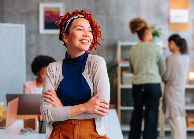 happy young businesswoman in office with colleagues in background
