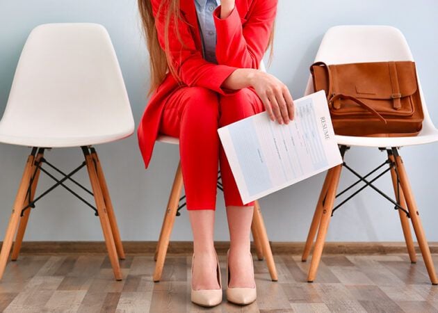 Woman in red suit sitting with resume awaiting job interview