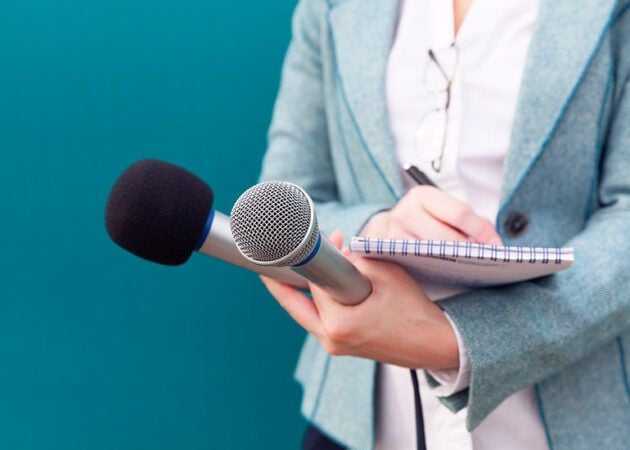 journalist holding microphone and notepad in media interview