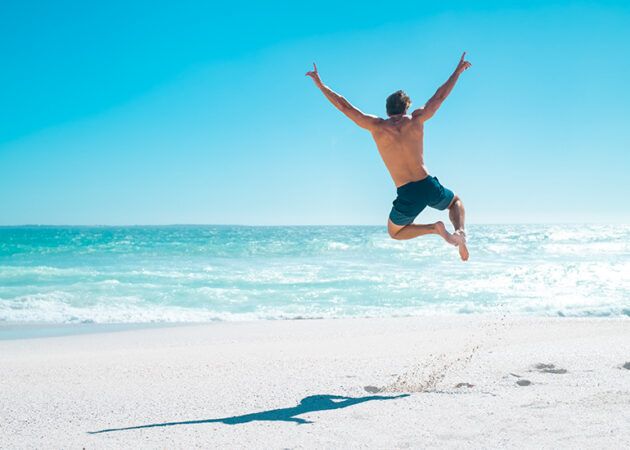 man jumping for joy on beach