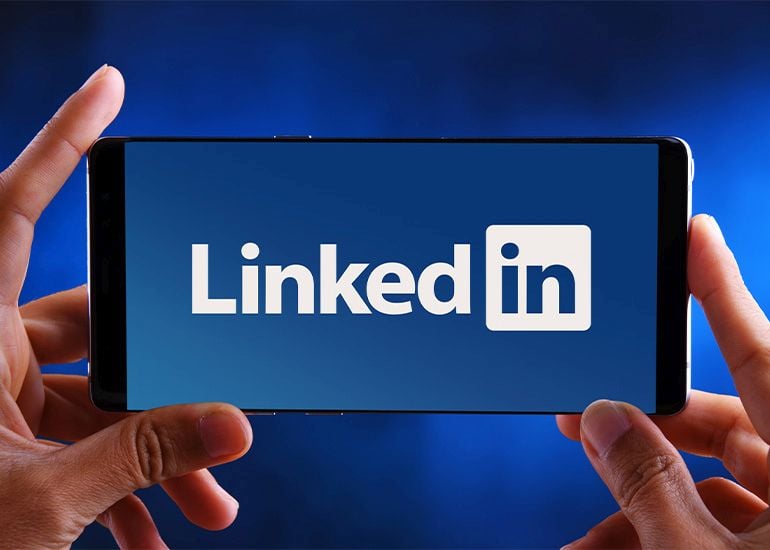 Hands holding phone with LinkedIn logo on screen