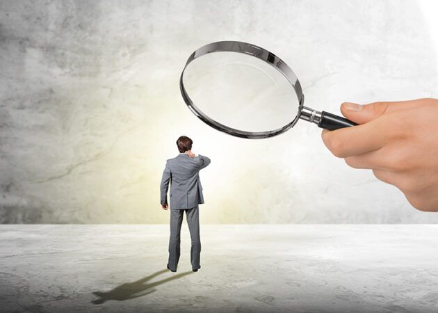 micromanager using magnifying glass to check on worker