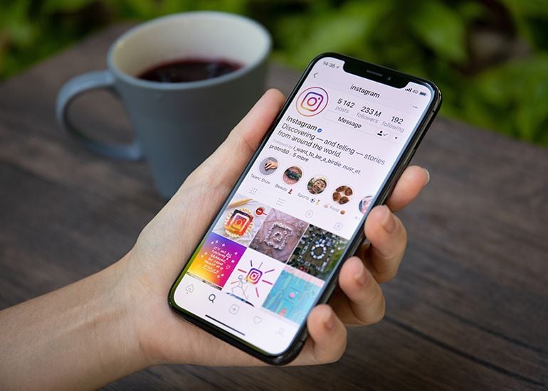 Hand holding smartphone with Instagram on screen