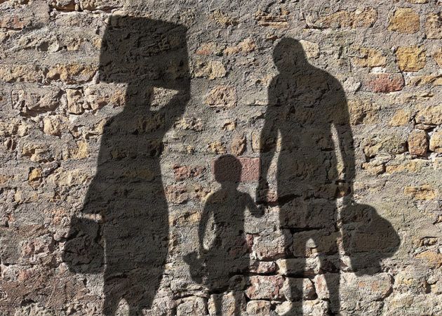 silhouette of migrant refugee family on brick wall