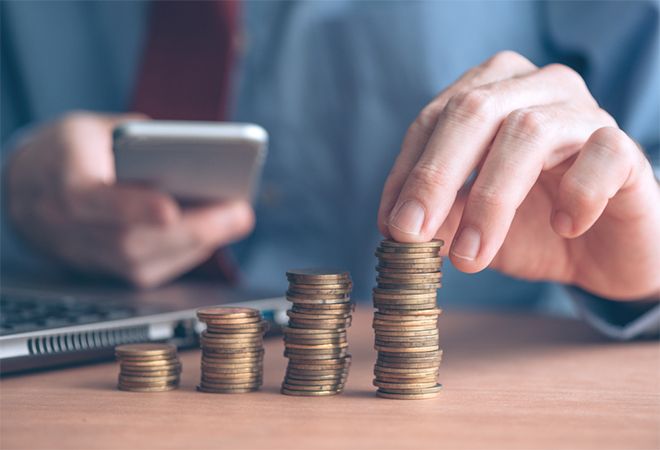 Man stacking coins while using phone