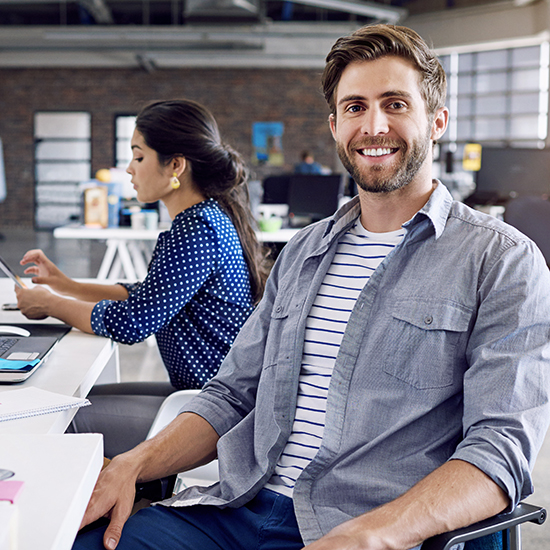 Smiling man sitting next to woman at desk in office
