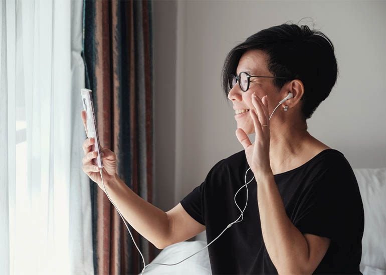 Woman waving at camera on phone