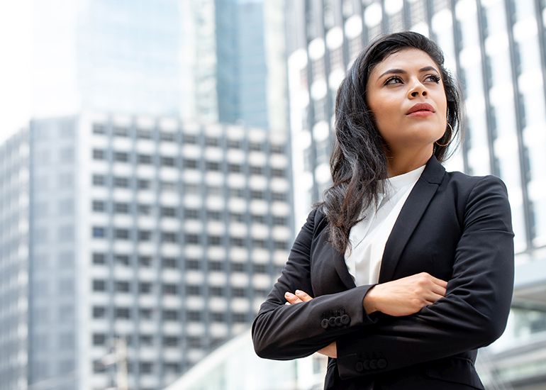 Powerful businesswoman leader standing in city with arms crossed