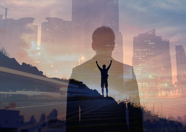 Man with arms raised in victory on hill overlooking city