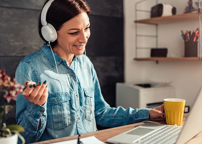 woman working on laptop at home with headphones