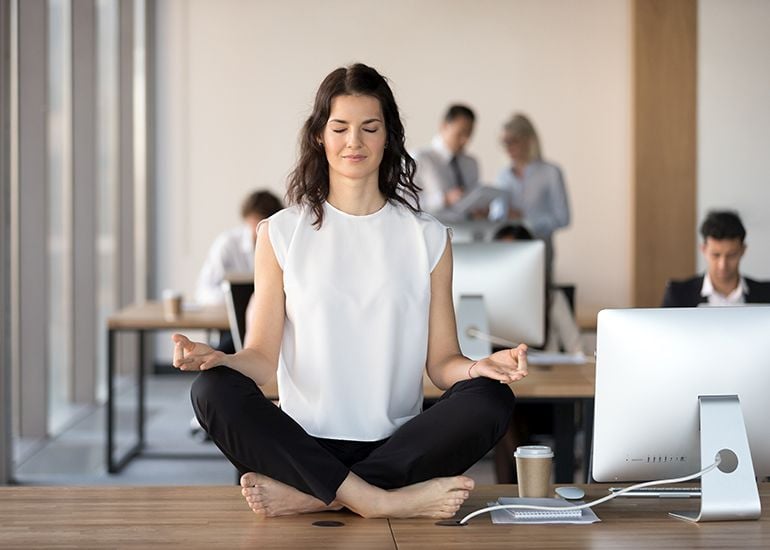 woman meditating on desk in work office