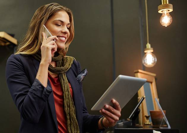 woman looking at an iPad as she makes an order over the phone - women in business concept
