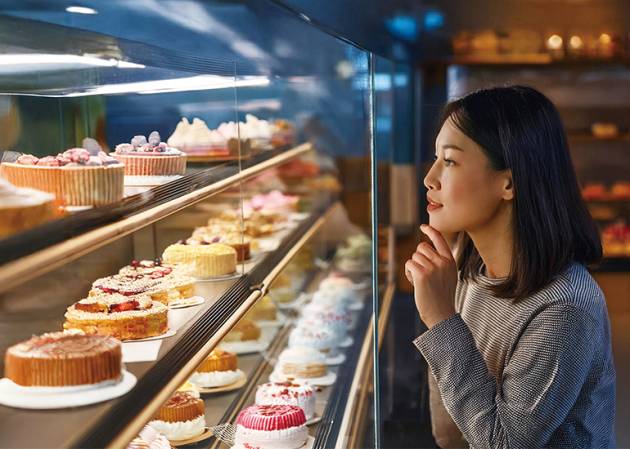 sale-ready business- woman choose from a cake dispaly at a bakery