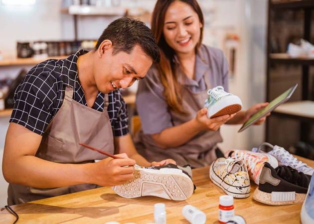 family business man customises a sneaker as woman looks on