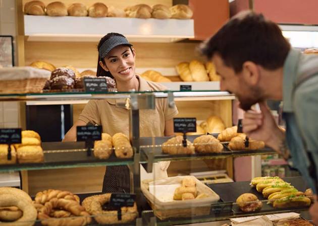 happy retailer in a bakery shop serving customer