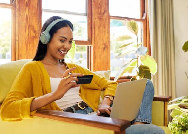 A smiling woman buys a product from her laptop with the help of Ai