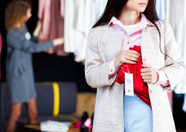 A shoplifter committing theft conceals a dress under their jacket