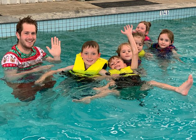 kids wave from pool during a swimming lesson