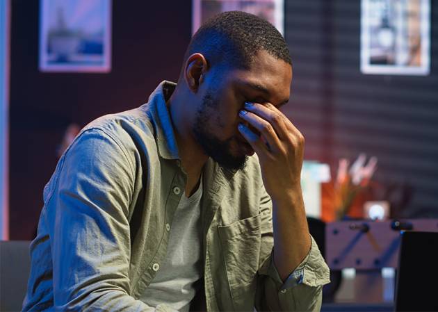 small business owner sitting at table head in hands feeling overworked and under pressure