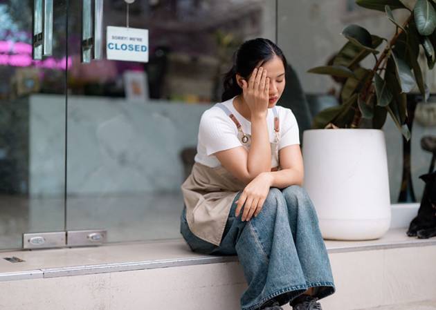 business woner sits on the stoop outside the store worried about inflation